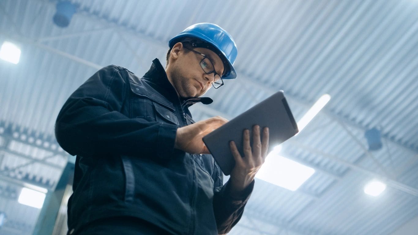 A man in a hard hat using a tablet.