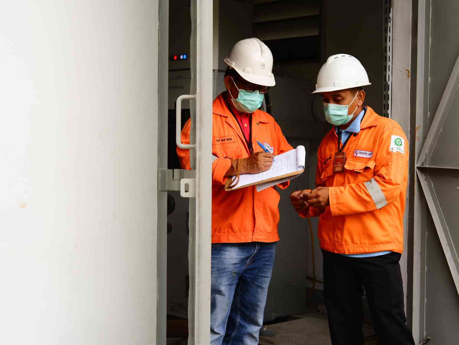 Two construction workers wearing masks and holding papers.