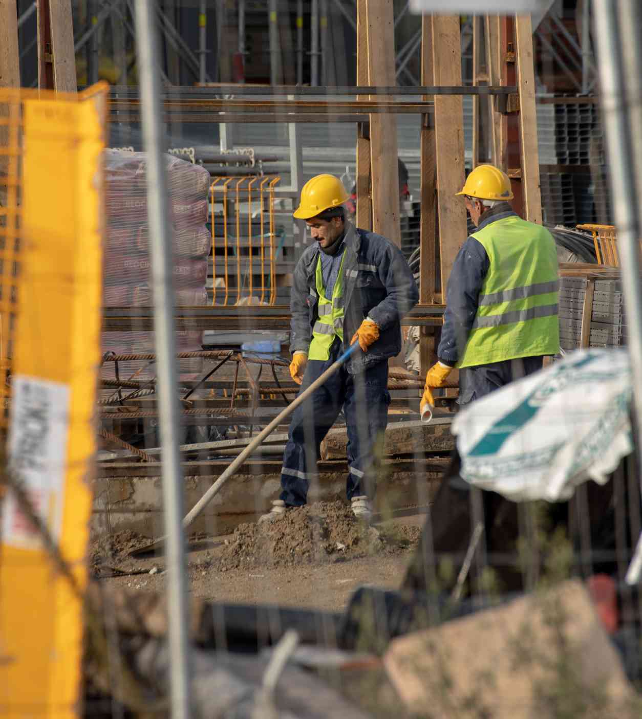 Two construction workers wearing yellow hard hats and gloves.