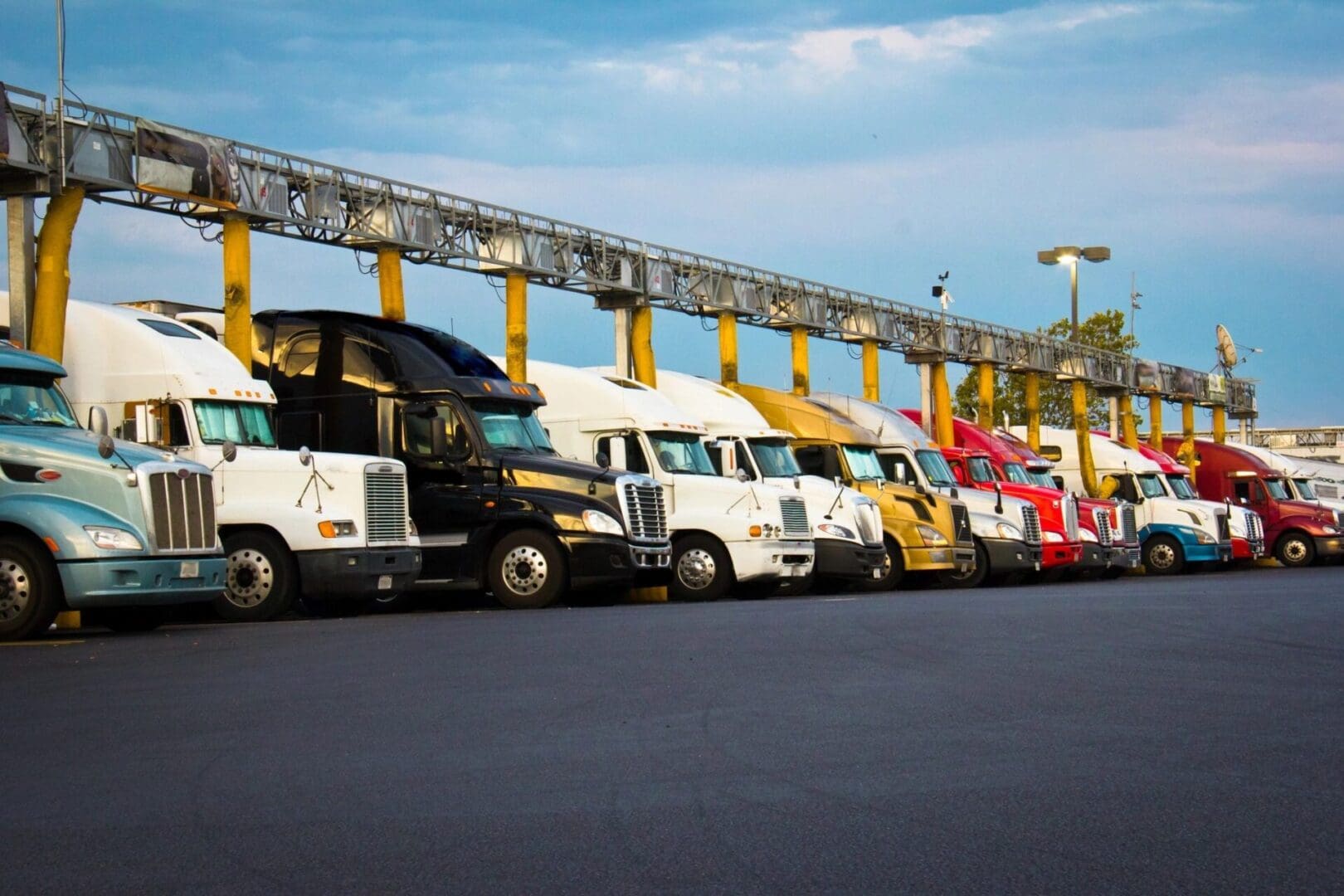 A line of trucks parked in front of a yellow fence.