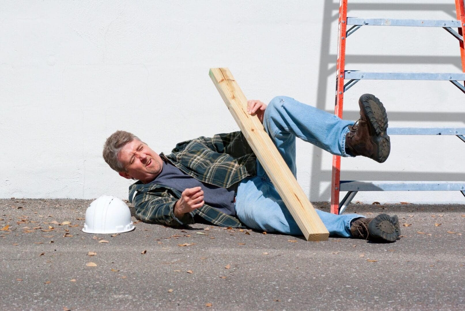 A man laying on the ground holding a wooden plank.